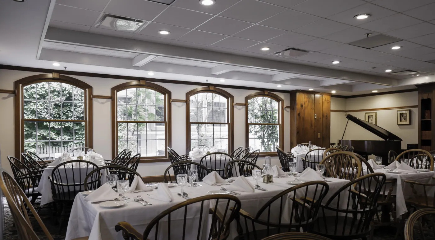 Dining room with arched windows, white linens and a piano